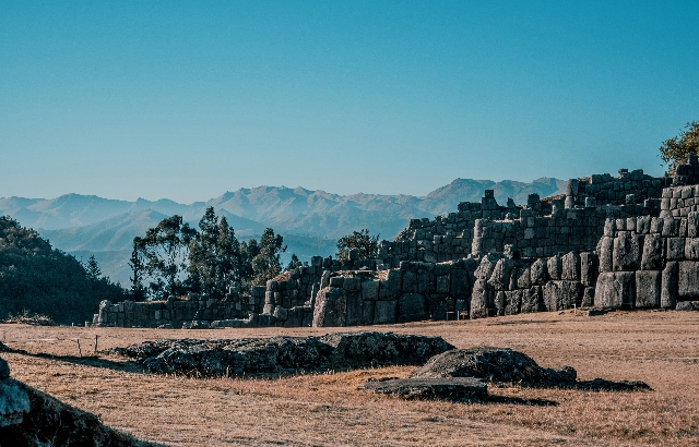 a stone structure in a field with mountains in the background_副本